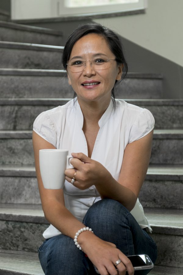 Lucy Dahlgren, founder of Bayn Solutions AB, sitting in a staircase with a cup of coffee